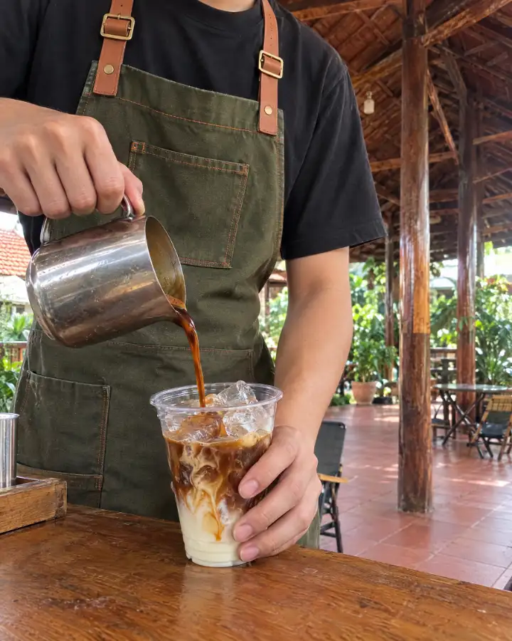 Barista rót cà phê vào ly đá